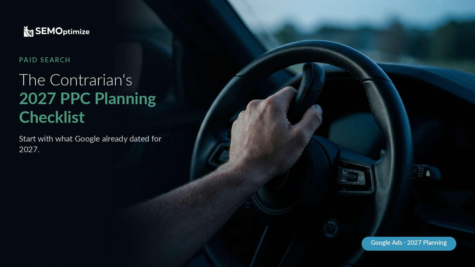 A driver's hand grips the steering wheel of a car at dusk, the road ahead soft and out of focus